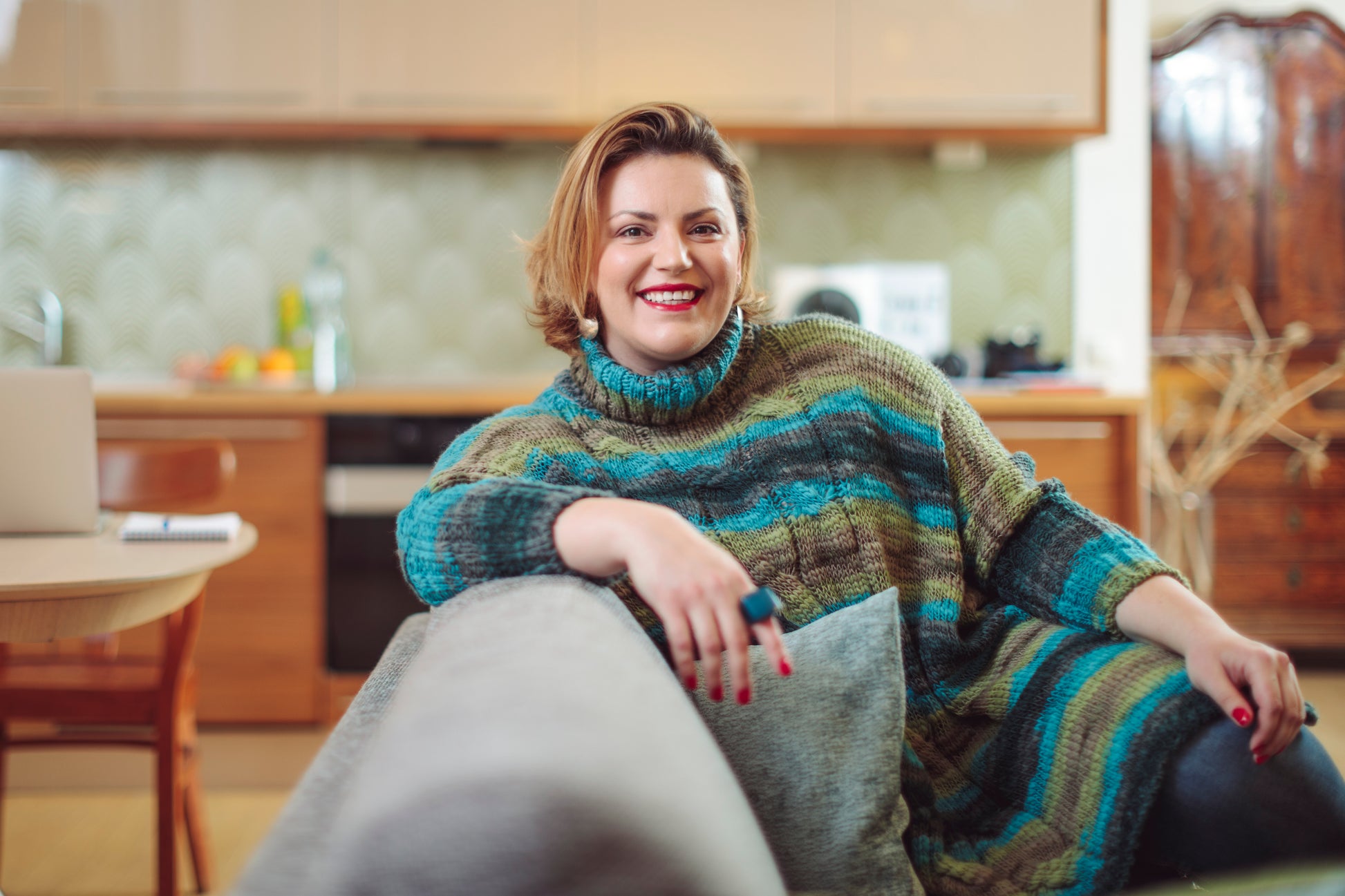 Woman sitting on a couch smiling at her skincare coach during a face to face consultation where they're planning a personalised skincare program